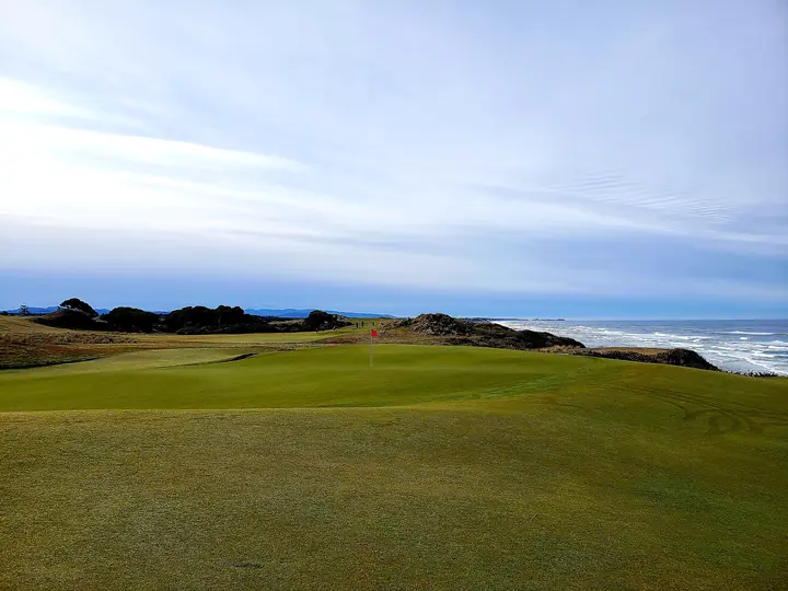 A green perched above the surf with the Pacific breaking along the shoreline.